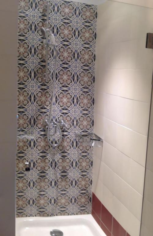 a bathroom with a shower with a tile wall at Hotel La Regence in Villefranche-sur-Mer