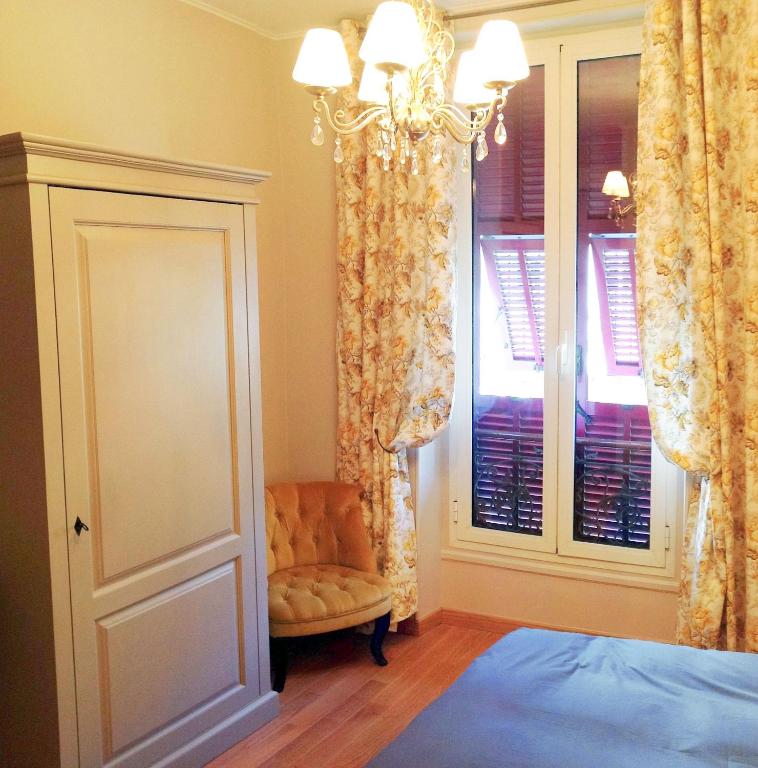 a bedroom with a bed and a chair and a window at Hotel La Regence in Villefranche-sur-Mer