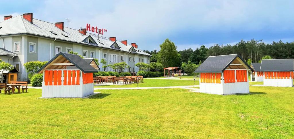 un hôtel avec des bâtiments orange et blancs dans l'herbe dans l'établissement Hotel TIREST, à Grebiszew