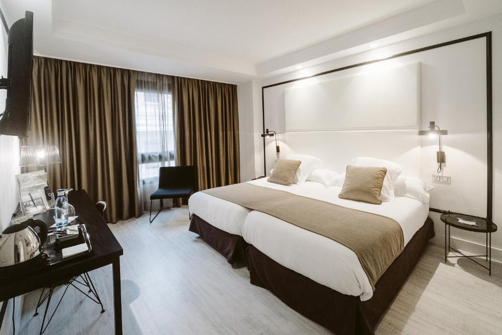 een hotelkamer met een groot bed en een bureau bij Hotel Abando in Bilbao