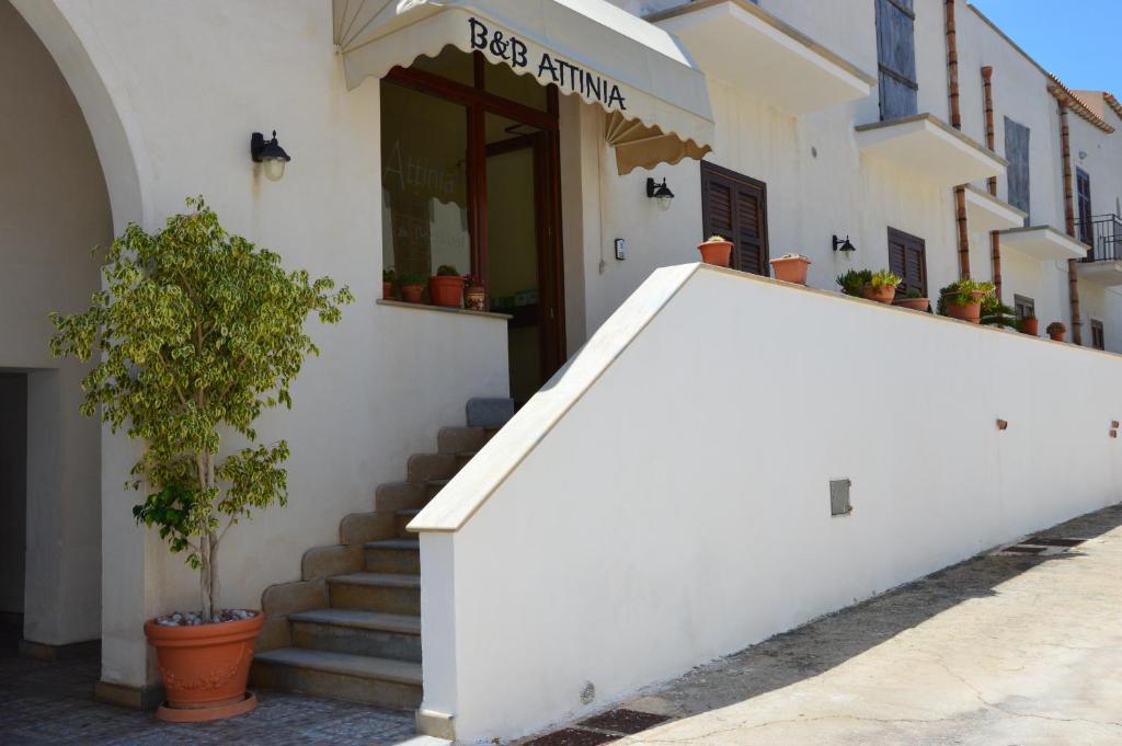 a white building with stairs and a plant in front at Attinia in San Vito lo Capo