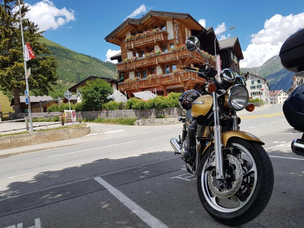 een gele motorfiets geparkeerd aan de kant van een straat bij Hotel Grimsel in Obergesteln