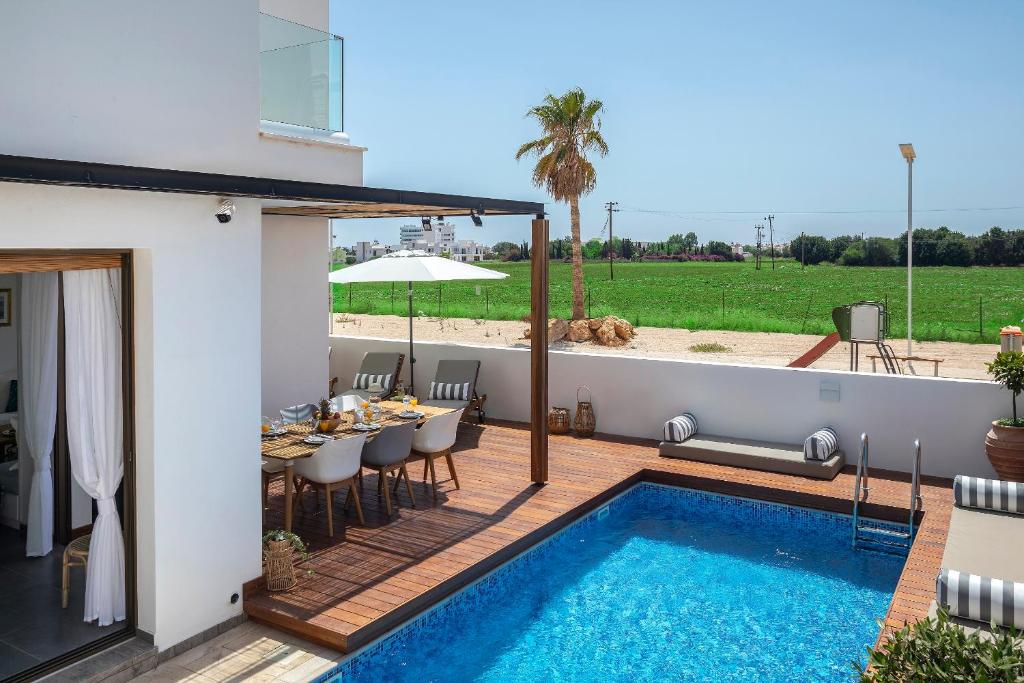 a patio with a dining table and a swimming pool at Chris Le Mare Luxury Villa in Protaras