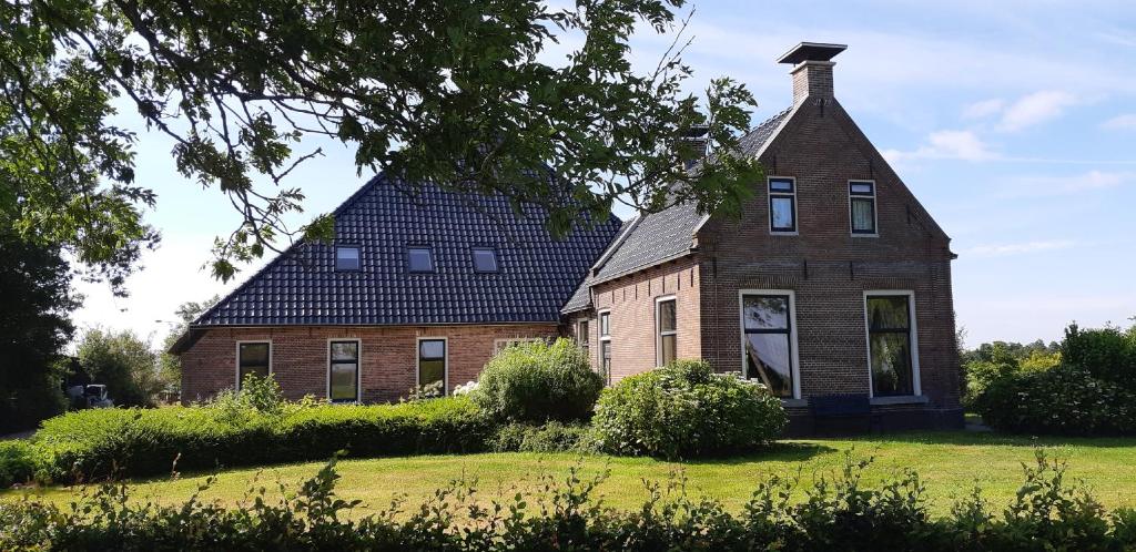 een oud stenen huis met een gambrel dak bij B&B De Warren in Suawoude