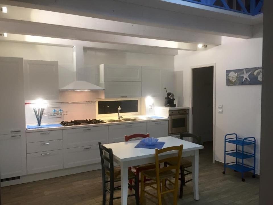 マリーナ・ディ・ジョイオーザ・イオーニカにあるCasa Azzurraのキッチン(テーブル、椅子付)、キッチン(白いキャビネット付)