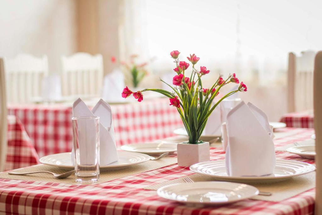 una mesa roja y blanca con platos y flores. en Windermere Inn, en Shillong