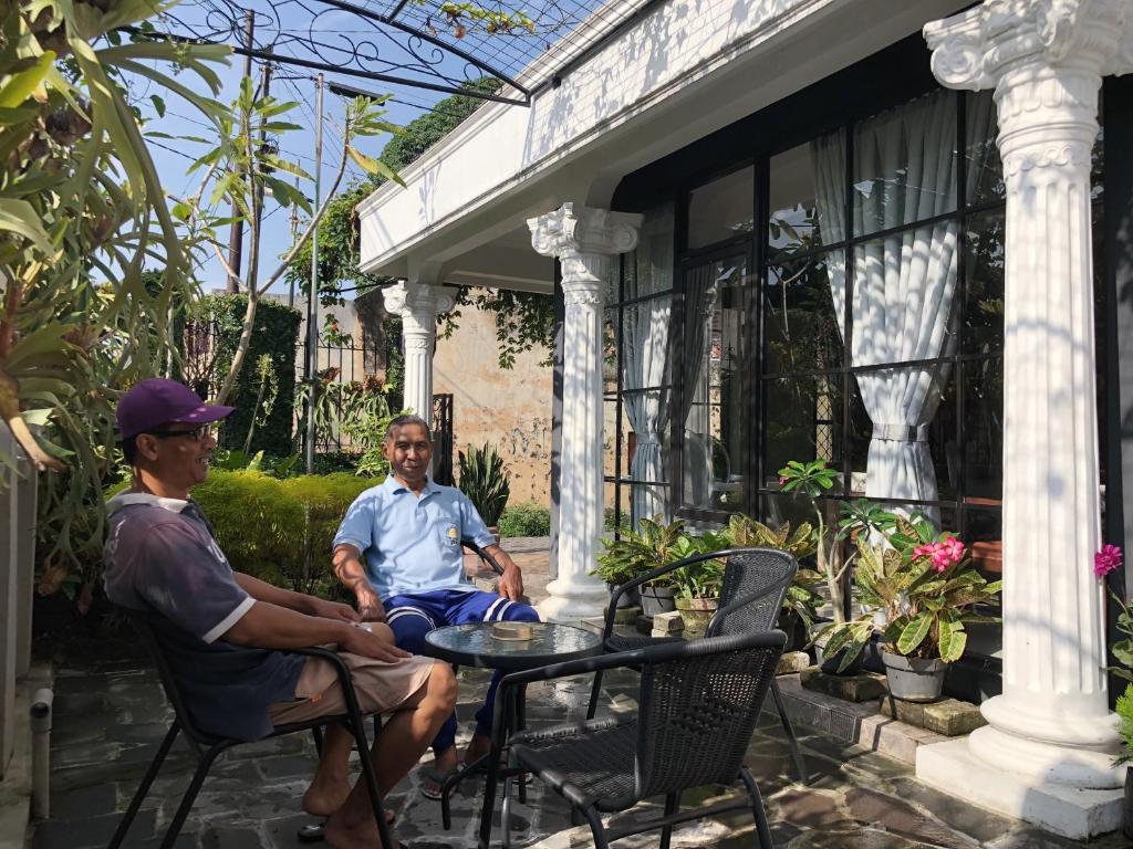 two men sitting on the porch of a house at Argya Guesthouse in Yogyakarta