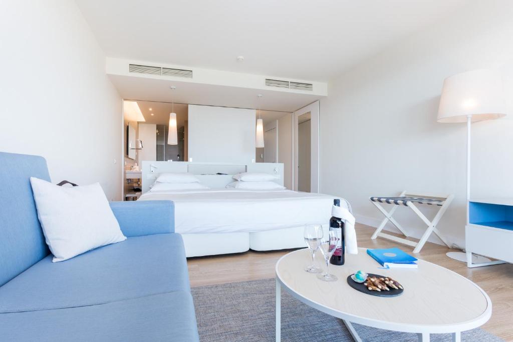 a bedroom with a bed and a table and a couch at Palmares Beach House Hotel - Adults Only in Lagos