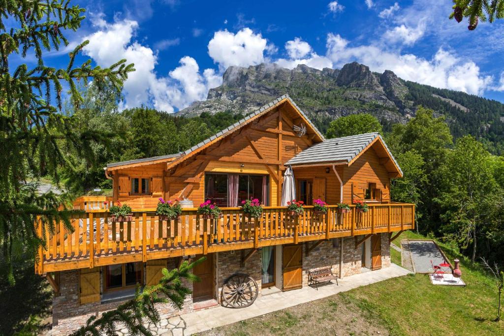 a log cabin with a balcony and mountains in the background at Gite&Spa le Montagnard in Saint-Jean-Saint-Nicolas