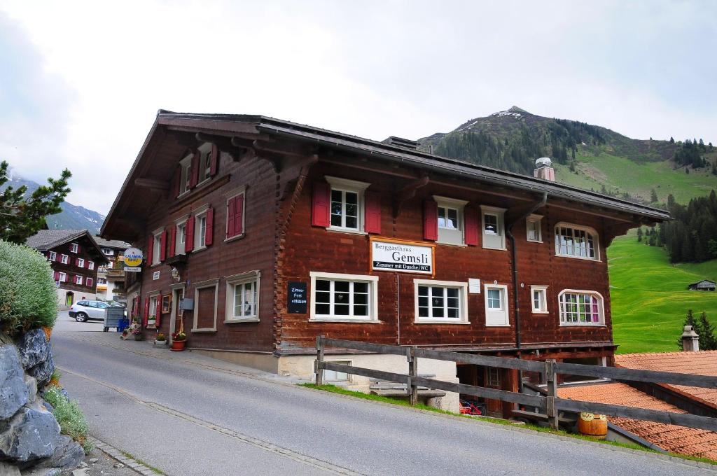 a large wooden building on the side of a street at Berggasthaus Gemsli in Sankt Antönien