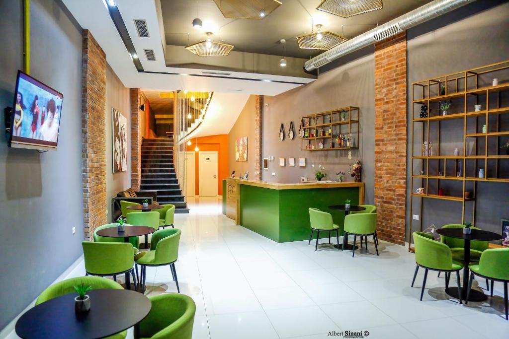 un restaurante con sillas y mesas verdes y un bar en Arc Hotel Tirana, en Tirana