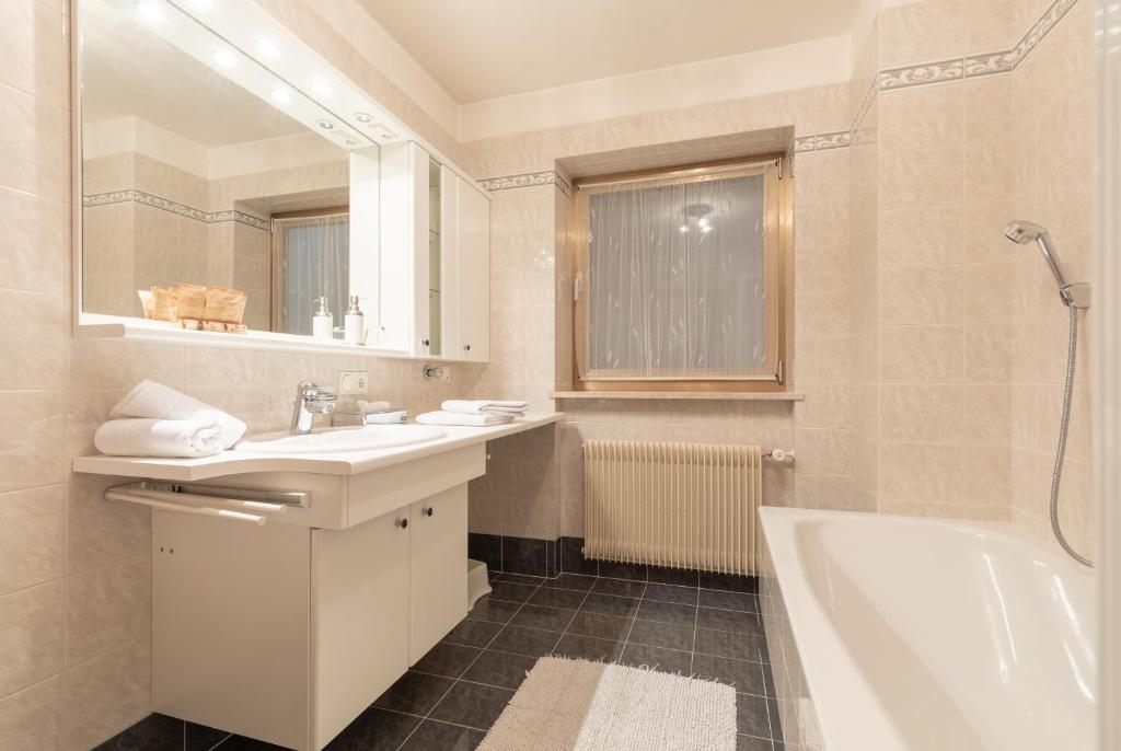 biała łazienka z wanną, umywalką i prysznicem w obiekcie Apartment Christian w mieście Nova Levante