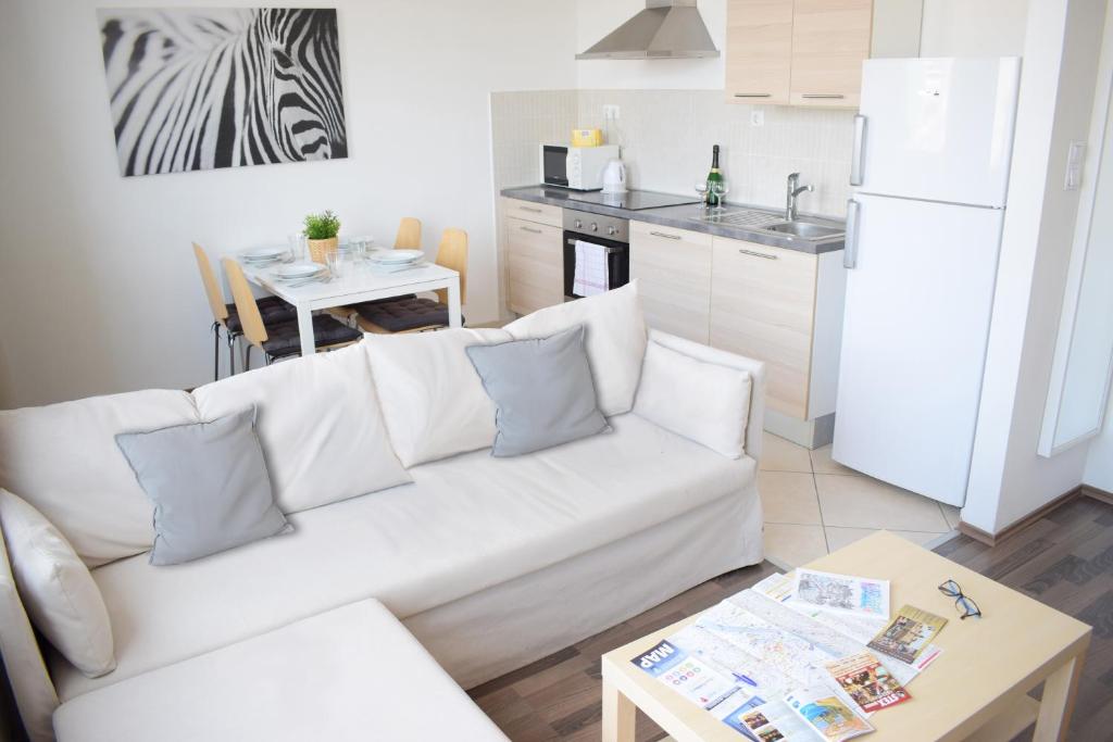 a living room with a white couch and a kitchen at Corvin Center Suites in Budapest