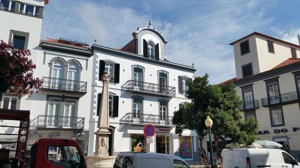 a white building with a clock tower on a street at Edificio Charles 102 in Funchal