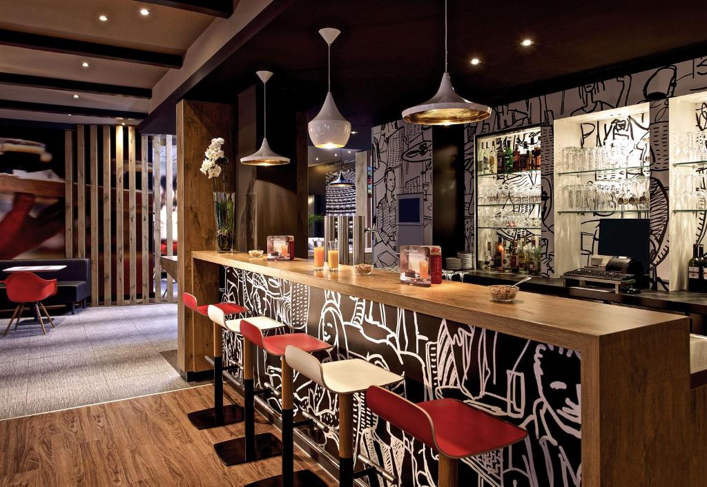 un restaurante con un bar con sillas rojas en ibis Bremen City, en Bremen