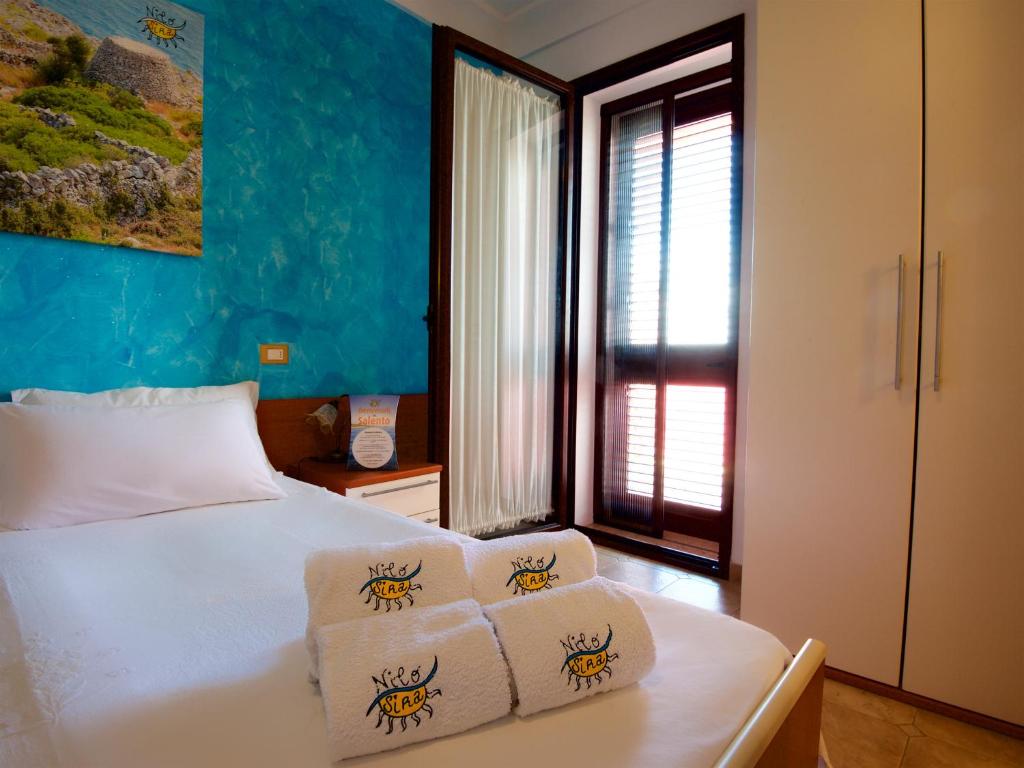 1 dormitorio con 1 cama con 3 toallas en B&B NiloSira, en Morciano di Leuca