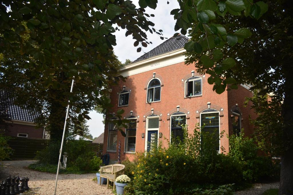 ein rotes Backsteinhaus mit einer Bank davor in der Unterkunft Tintaglia, betaalbaar en gastvrij in Stadskanaal