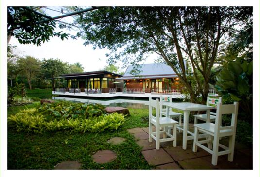 een tafel en stoelen voor een gebouw bij Young Coconut Garden Home Resort in Amphawa