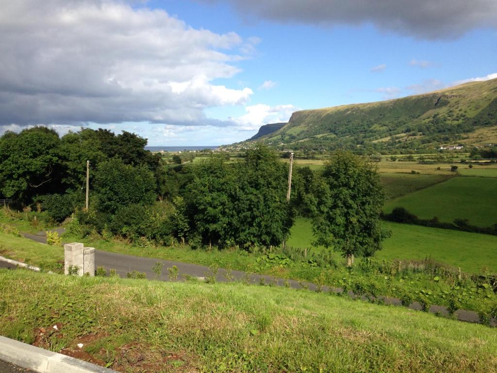 uma estrada num campo com montanhas ao fundo em Applewood Heights em Glenariff