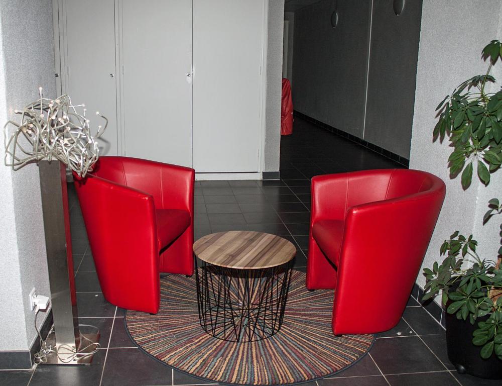 two red chairs and a table in a room at City Lodge Appart Hôtel Niort in Niort