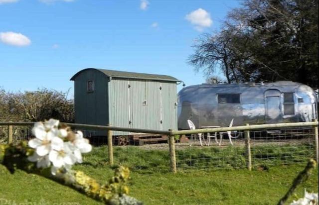 a trailer sitting in a field next to a fence at Ludlow Vintage Airstream in Ludlow