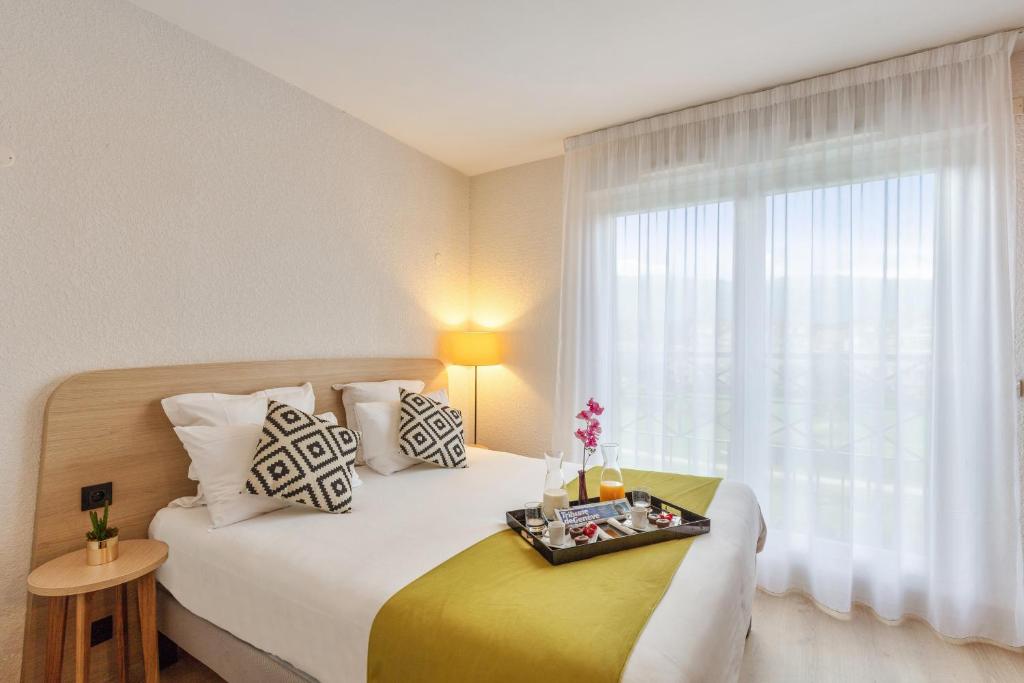 a bedroom with a bed with a tray of food on it at Zenitude Hôtel-Résidences Divonne Confort in Divonne-les-Bains