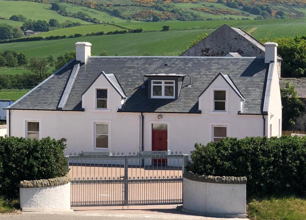 una casa bianca con un tetto nero e una recinzione di Bridgemill a Girvan