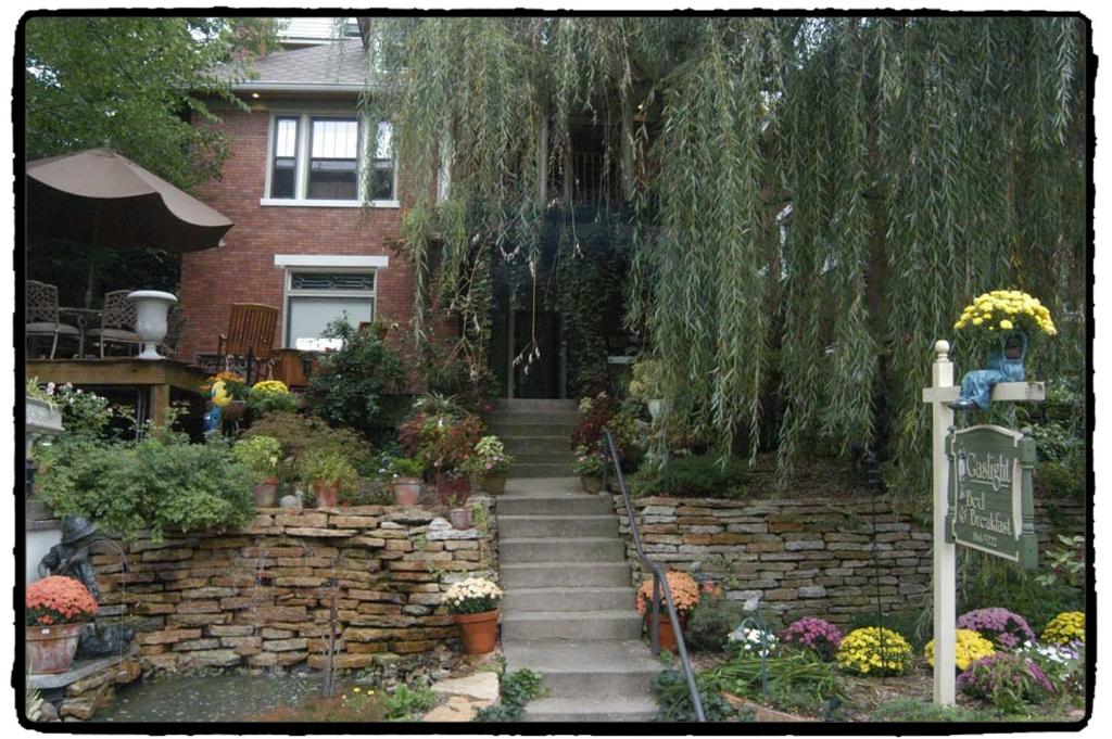 a garden with a stone wall and stairs with flowers at Gaslight Bed & Breakfast in Cincinnati