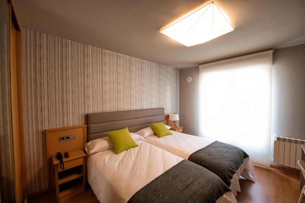 1 dormitorio con 1 cama grande con almohadas verdes en Hotel VIDA Mar de Laxe en Laxe