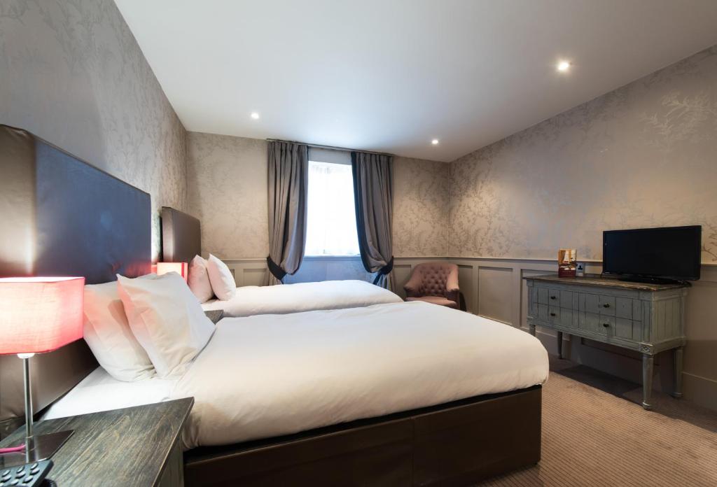 a bedroom with two beds and a desk and a television at Brooks Hotel in Edinburgh