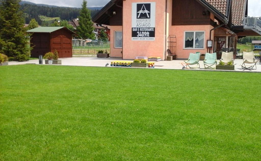a yard with green grass in front of a building at B&B 3409ft Aeroporto in Asiago