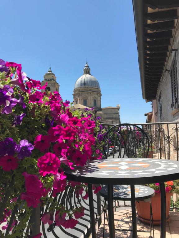 a table and chairs on a balcony with flowers at Camere il Cantico in Assisi