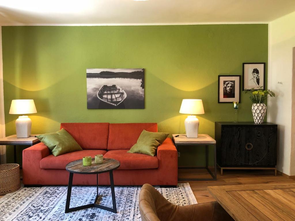 een woonkamer met een rode bank en een groene muur bij Style Apartments by Mieze Schindler in St. Wolfgang