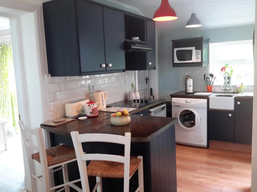 uma cozinha com armários pretos e uma ilha de cozinha com cadeiras em Grove lodge em Aglish