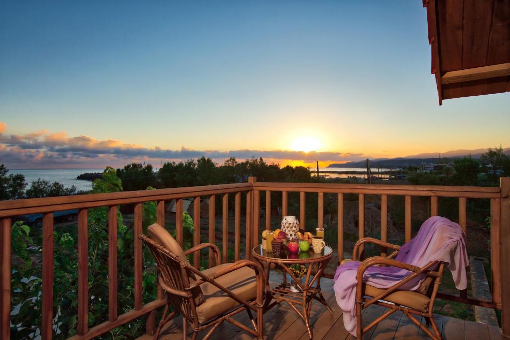 einen Tisch und zwei Stühle auf einem Balkon mit Blick auf den Sonnenuntergang in der Unterkunft Villa Kallia & George in Malia