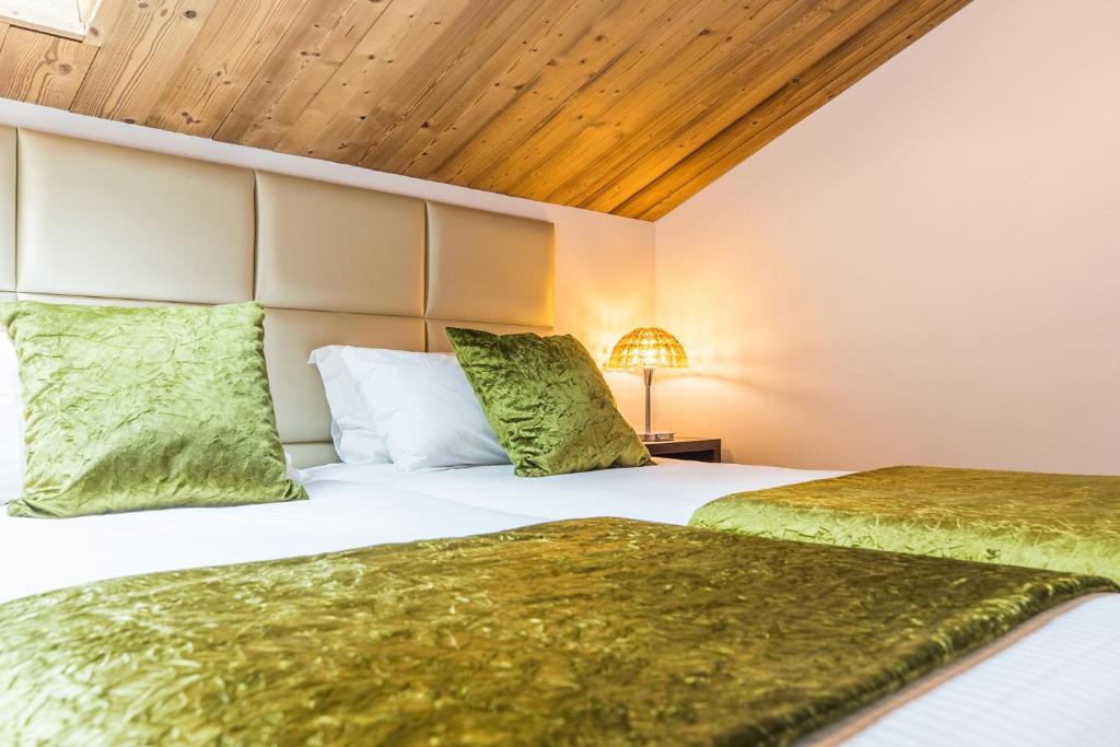 two beds with green pillows in a room at Madame Vacances Hôtel & Spa Le Mottaret in Méribel
