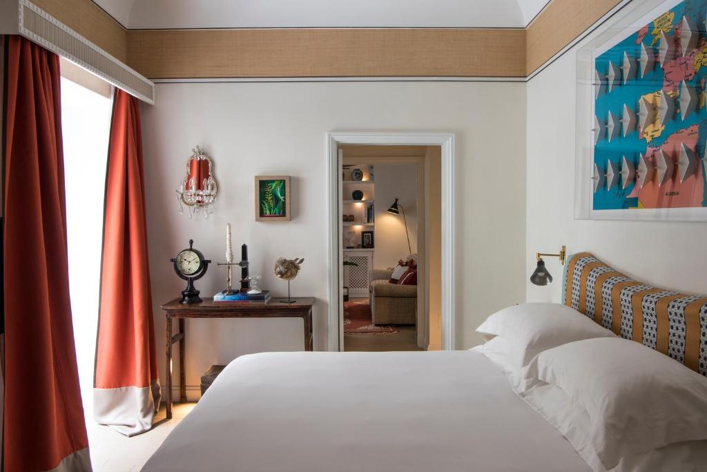 a bedroom with a white bed and a living room at Capri Tiberio Palace - The Leading Hotels of the World in Capri