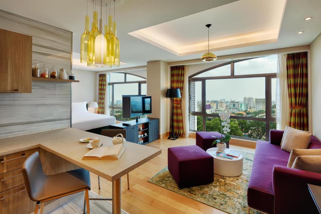 Sherwood Suites في مدينة هوشي منه: غرفة معيشة مع أريكة وغرفة طعام