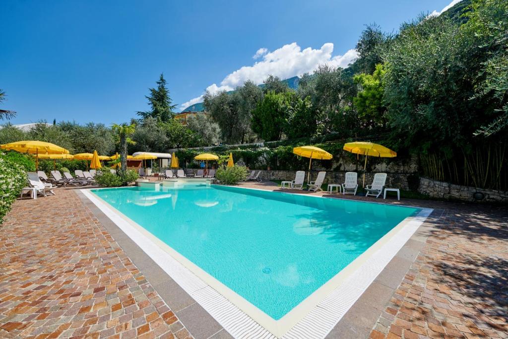 a swimming pool with chairs and umbrellas at Hotel Catullo in Malcesine