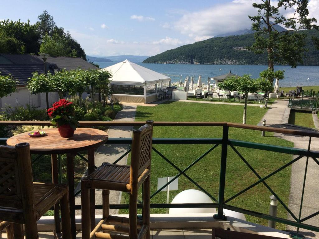 d'un balcon avec une table et des chaises et une vue sur l'eau. dans l'établissement la baie des voiles ,vue lac d'Annecy ,plage privée, à Duingt
