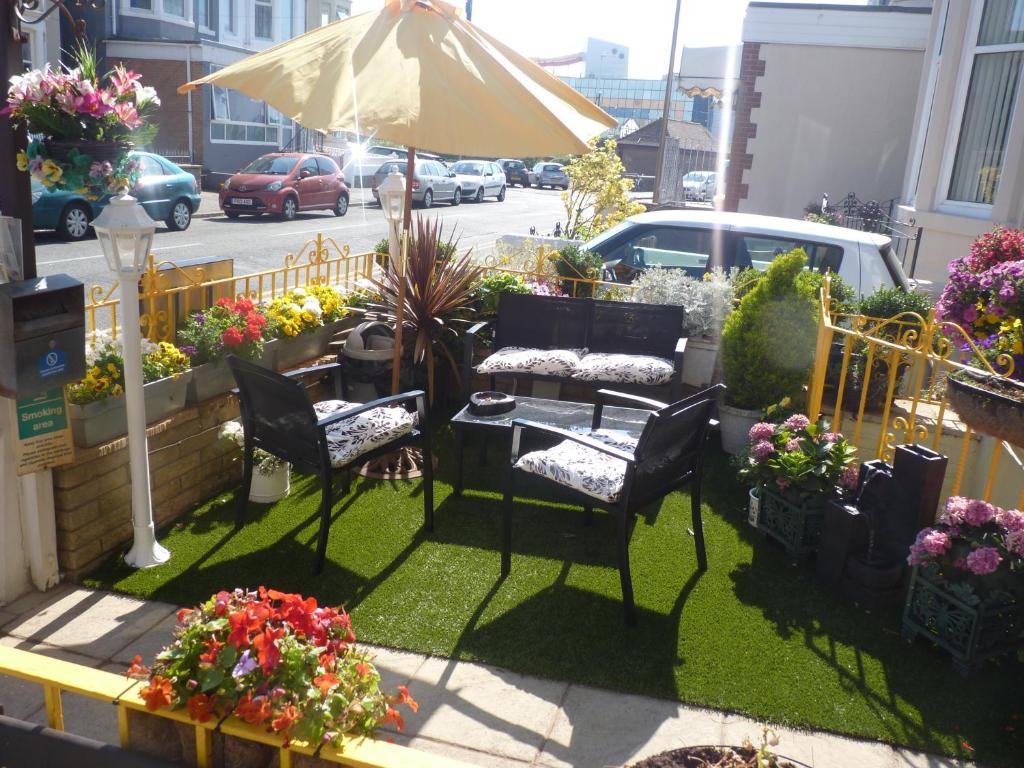 a patio with two chairs and an umbrella and flowers at The Berkswell in Blackpool