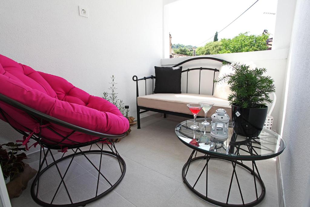 a balcony with two chairs and a table with wine glasses at Apartman Tara in Split