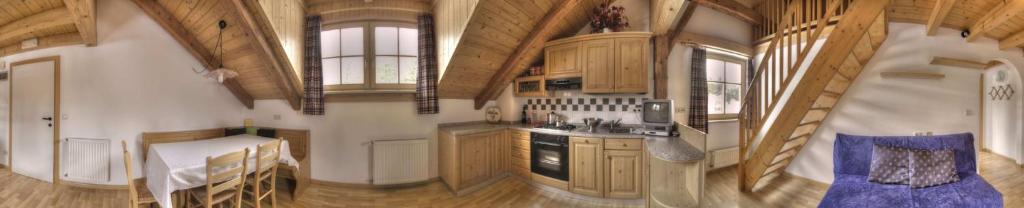 une grande cuisine avec des placards en bois et une salle à manger dans l'établissement Apartments & Relax Greta, à Dobbiaco