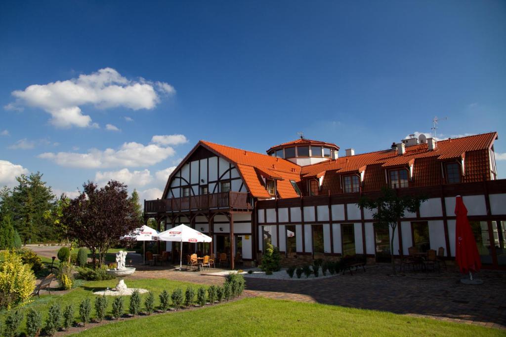 un grand bâtiment avec un toit orange et une cour dans l'établissement Hotel Karolinka, à Gogolin