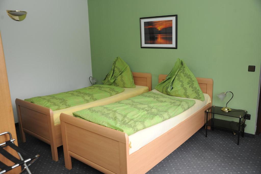2 Betten in einem Zimmer mit grüner Bettwäsche in der Unterkunft Pension Erlaa in Wien