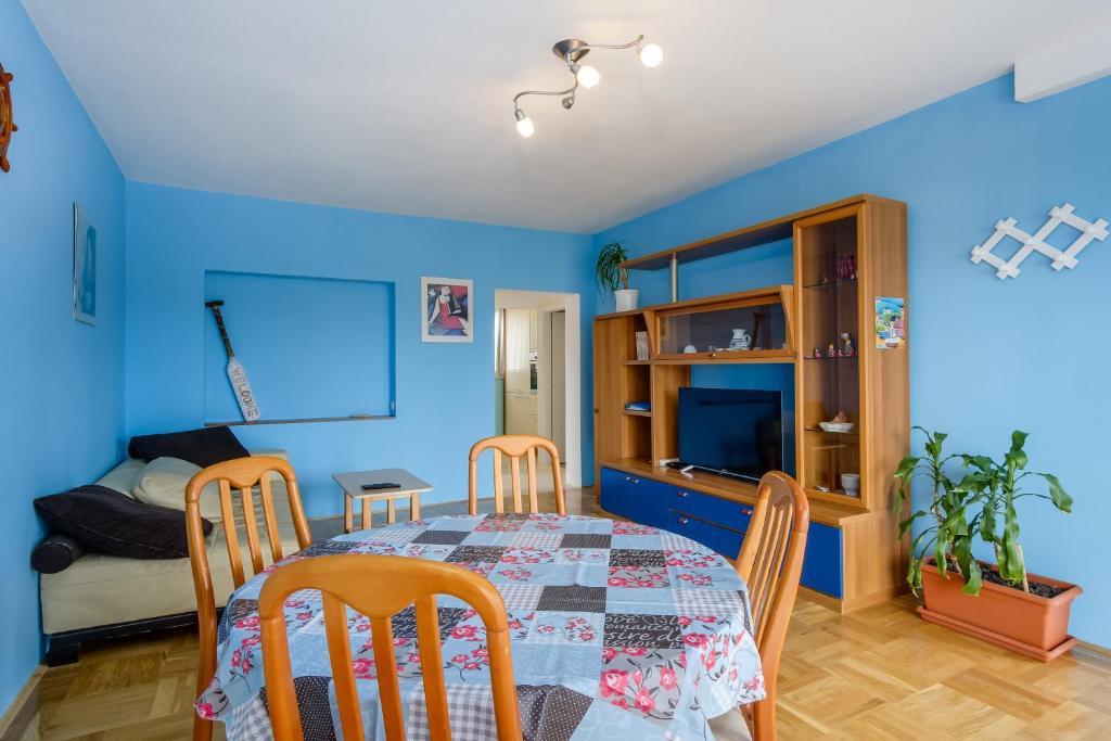 ein Esszimmer mit blauen Wänden sowie einem Tisch und Stühlen in der Unterkunft KON-TIKI Apartments in Mali Lošinj