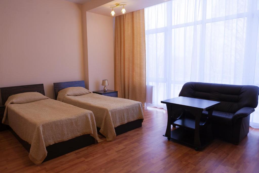a hotel room with a bed and a couch and a chair at Apart Hotel Cherepovets in Cherepovets