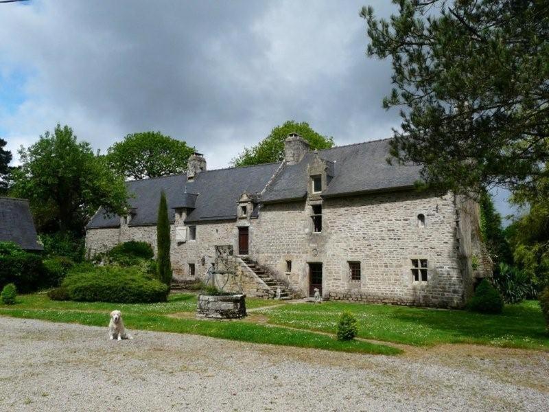 un perro parado frente a un gran edificio de piedra en Manoir de Keroman, en Languidic