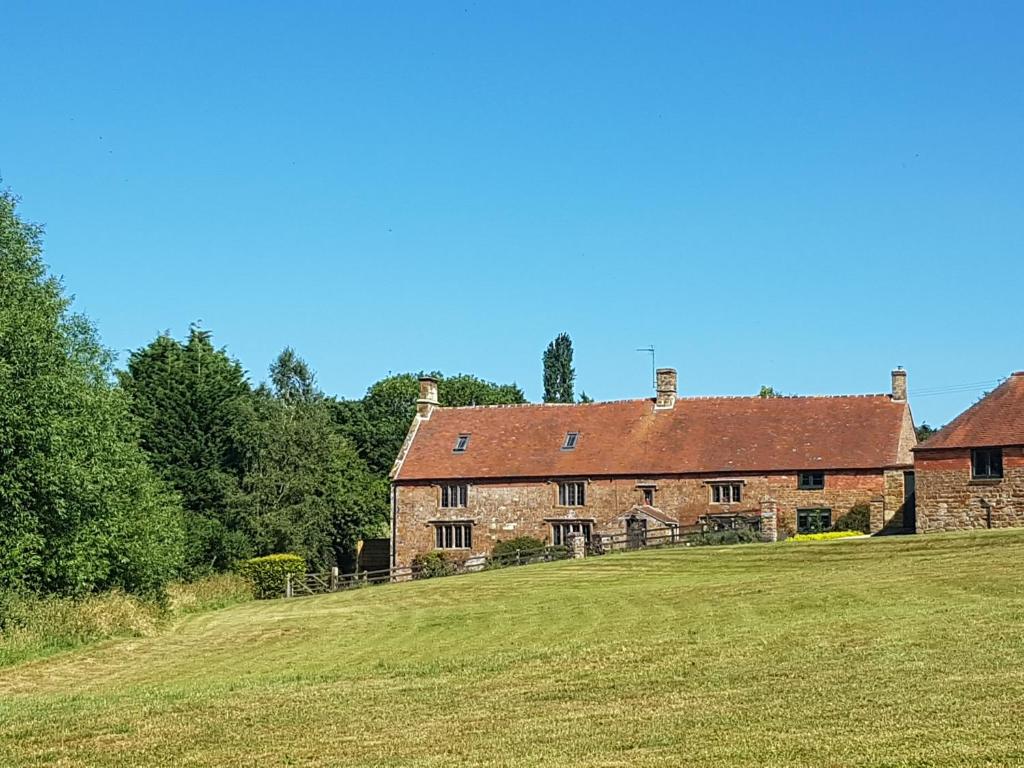 an old brick house with a grass field in front of it at Hollow Meadow House in Priors Marston