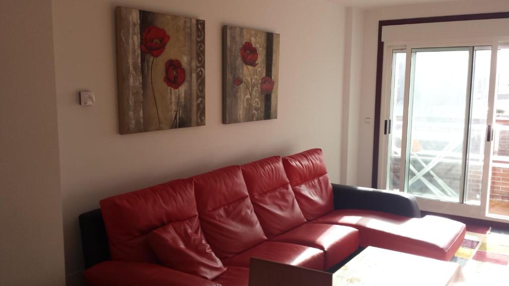 a red leather couch in a living room with a window at Apartamento O pombal in Cambados
